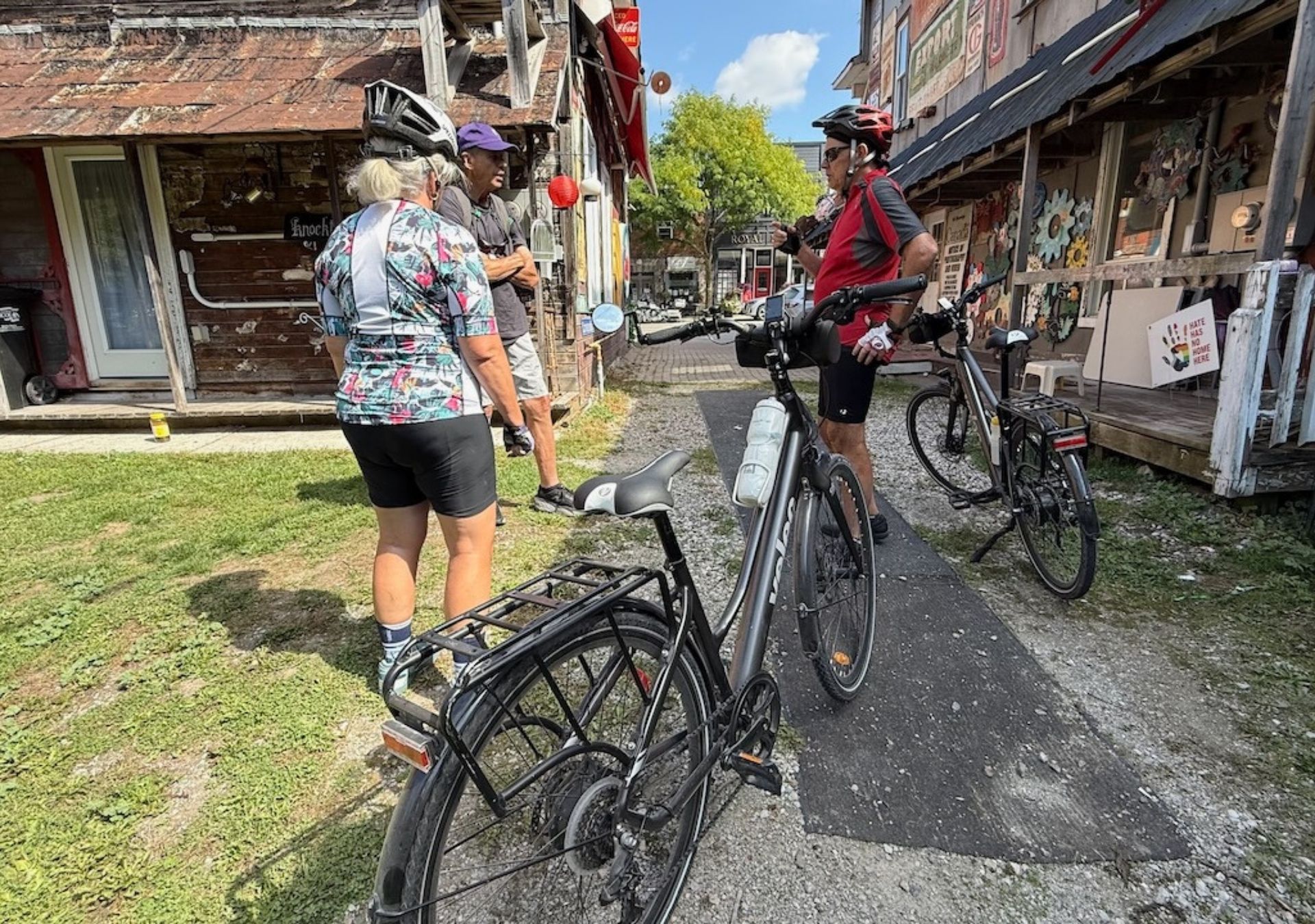Cyclists near vintage storefronts outdoors.
