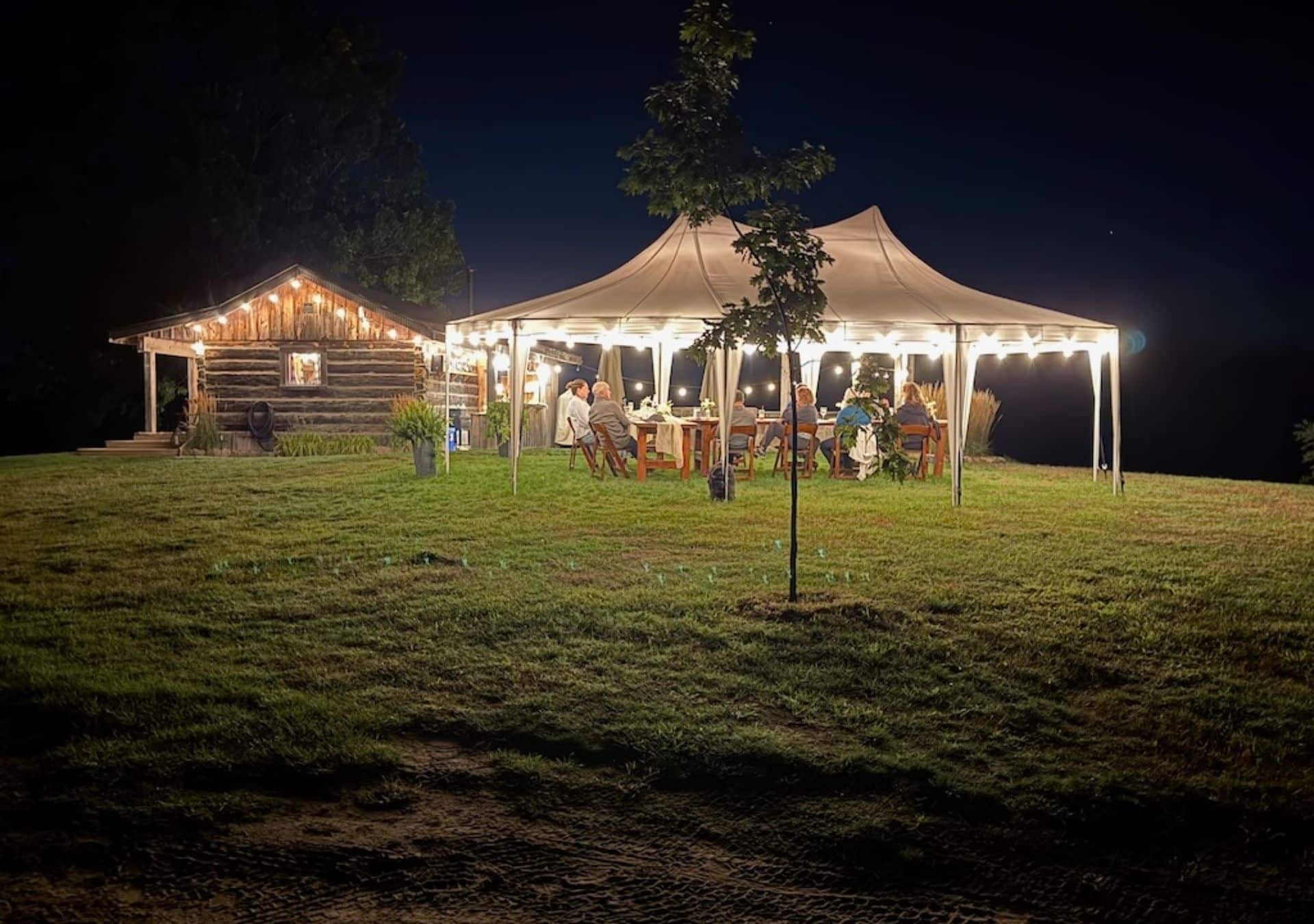 Outdoor gathering under tent at night